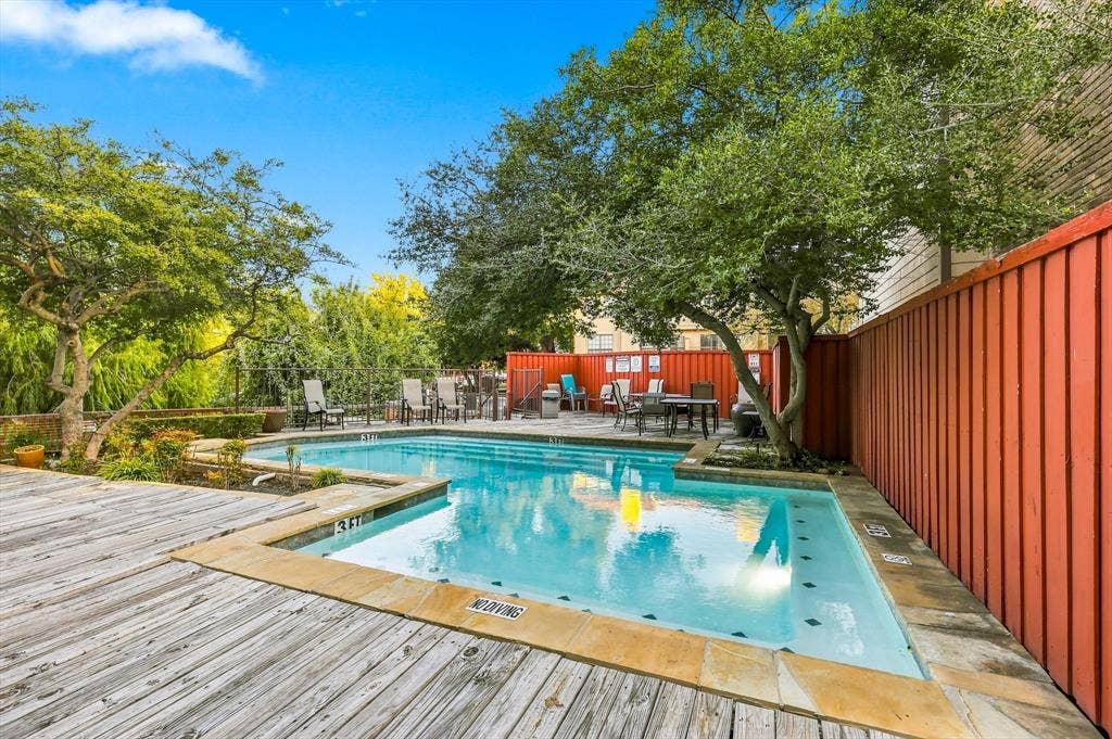 4777 Cedar Springs Road, #9K, Dallas, TX 75219 Outdoor swimming pool featuring a stone-tile border, wood-finish decking, and perimeter fencing