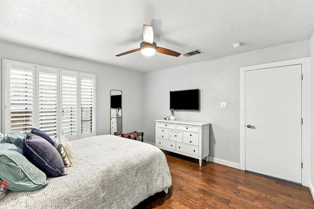 4777 Cedar Springs Road, #9K, Dallas, TX 75219 Room featuring wood-finish flooring, plantation shutters, and a central ceiling fan with integrated lighting