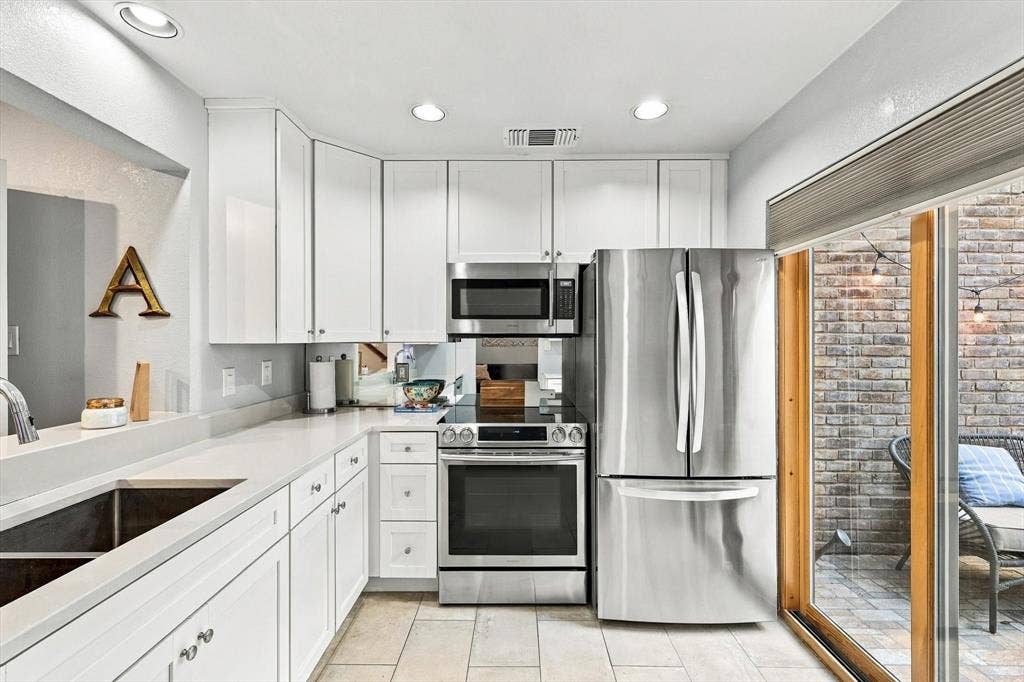 4777 Cedar Springs Road, #9K, Dallas, TX 75219 Kitchen featuring white cabinetry, solid-surface countertops, recessed ceiling lighting, stainless steel appliances, and tile flooring