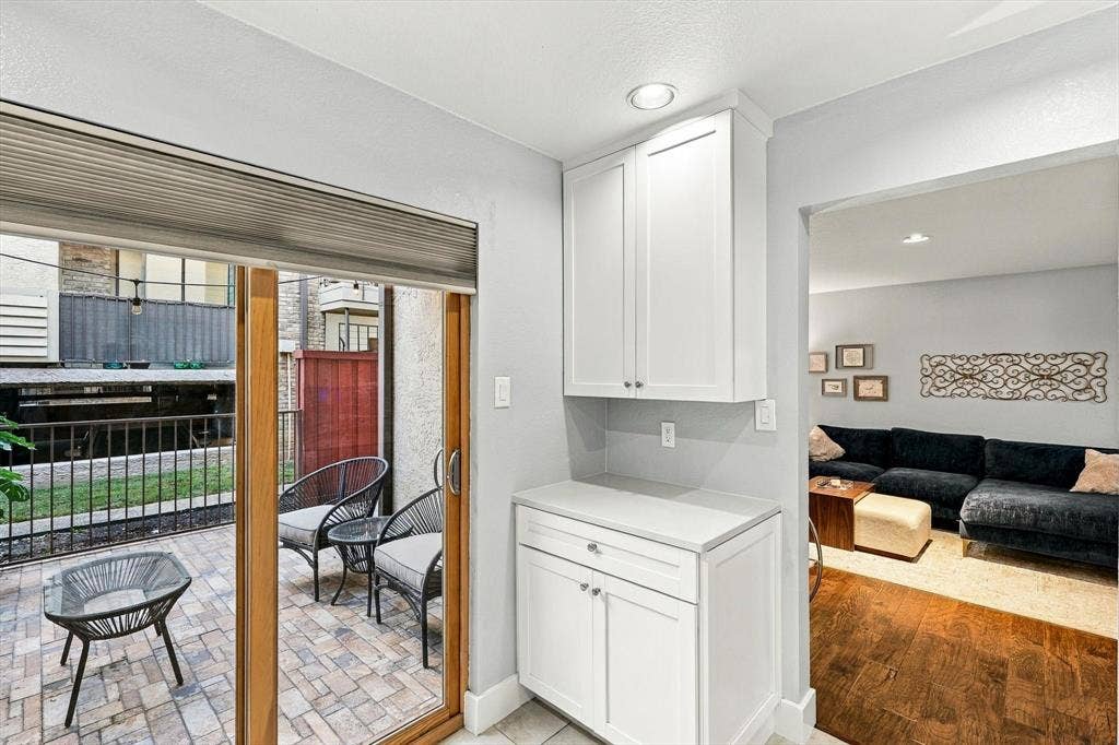 4777 Cedar Springs Road, #9K, Dallas, TX 75219 Built-in white cabinetry with stone-surface countertop, sliding glass door, recessed lighting, and paver-stone patio