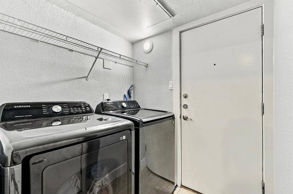 4777 Cedar Springs Road, #9K, Dallas, TX 75219 Laundry utility space access garage featuring a metal wire wall-mounted shelving unit and a solid core door with a security deadbolt