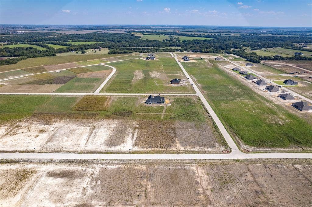 109 Devi Drive, Waxahachie, TX 75165 Aerial perspective of expansive residential acreage featuring cleared lots, paved roadways, and surrounding wooded borders