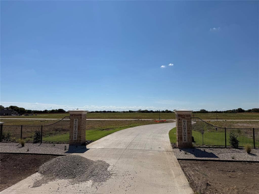 109 Devi Drive, Waxahachie, TX 75165 Concrete driveway entrance featuring brick-faced stone pillars and black metal perimeter fencing