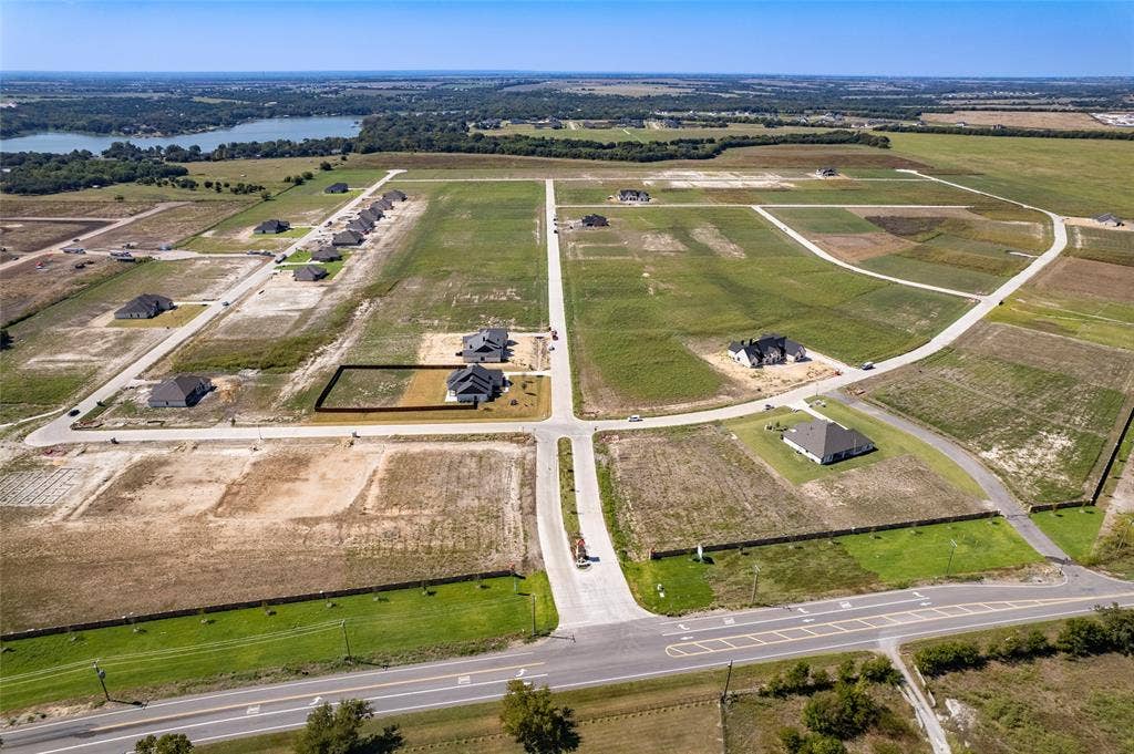 109 Devi Drive, Waxahachie, TX 75165 Aerial perspective of residential lots featuring paved roads, concrete infrastructure, and proximity to a water reservoir