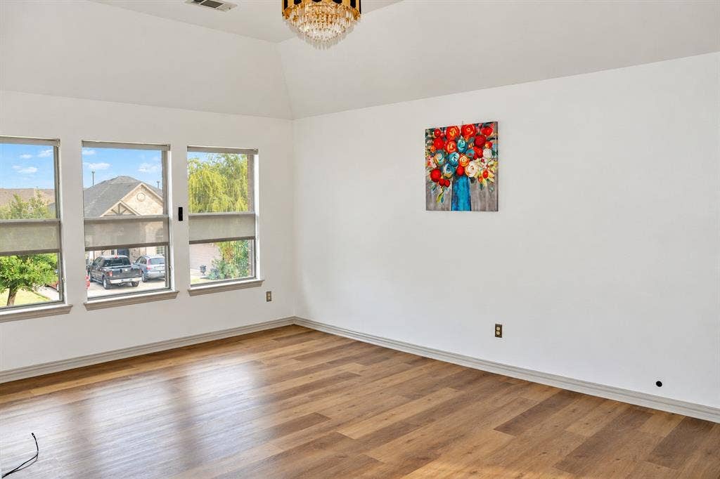 3620 Carlton Court, Sachse, TX 75048 Vaulted ceiling with a multi-tiered crystal chandelier, wood-finish flooring, and expansive windows