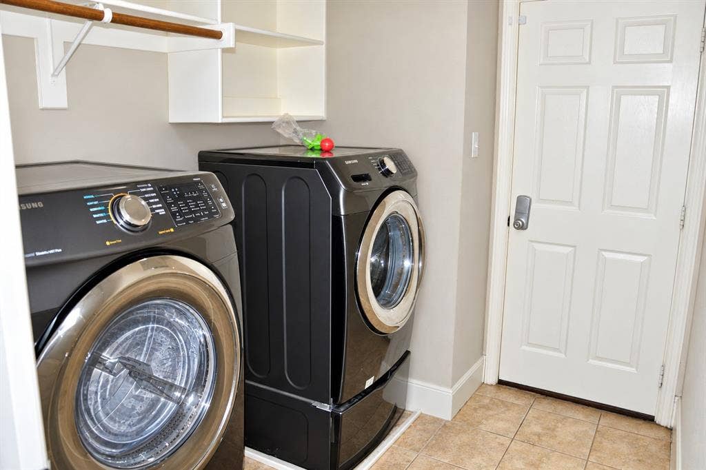 3620 Carlton Court, Sachse, TX 75048 Utility room featuring ceramic tile flooring, built-in white shelving with a hanging rod, and a six-panel door with metal hardware