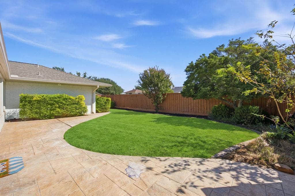 6978 Pemberton Drive, Dallas, TX 75230 Backyard featuring a stamped concrete patio, manicured lawn, perimeter wood fencing, and established trees