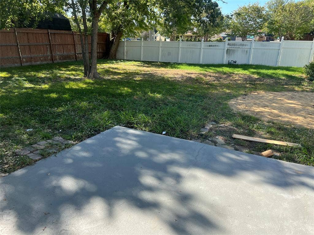 5005 Highridge Drive, Garland, TX 75043 Backyard featuring a concrete patio, grass lawn, mature trees, and privacy fencing