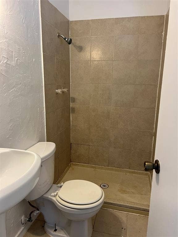 5005 Highridge Drive, Garland, TX 75043 Shower stall featuring full-height square ceramic tile surround, integrated shower head, and floor-mounted toilet