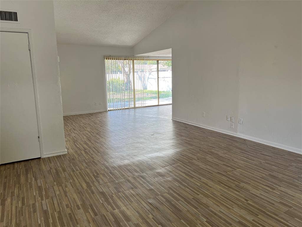 5005 Highridge Drive, Garland, TX 75043 Open-concept room featuring vaulted ceilings, wood-finish flooring, and sliding glass doors