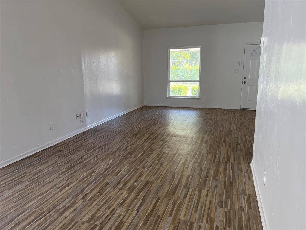 5005 Highridge Drive, Garland, TX 75043 Interior space featuring wood-finish flooring, vaulted ceilings, neutral wall tones, and an exterior door with a window insert