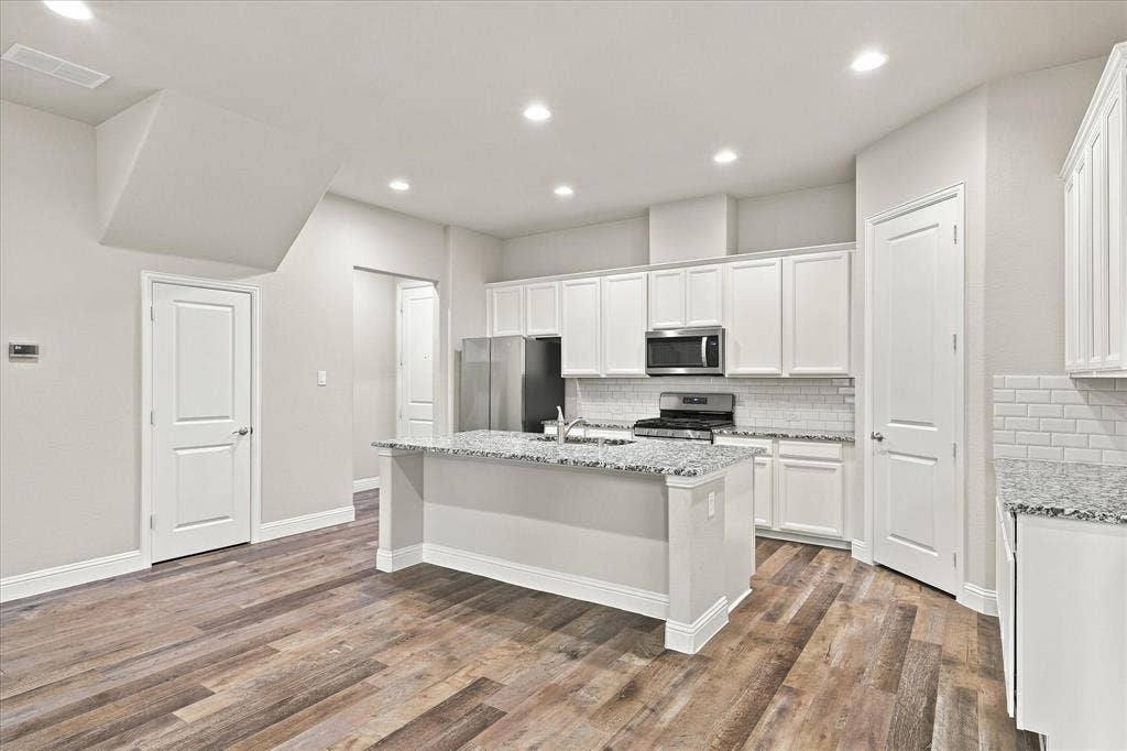 614 Ansley Way, Allen, TX 75013 Kitchen featuring a central island with stone-finish countertops, white shaker-style cabinetry, subway tile backsplash, stainless steel appliances, and wood-finish flooring
