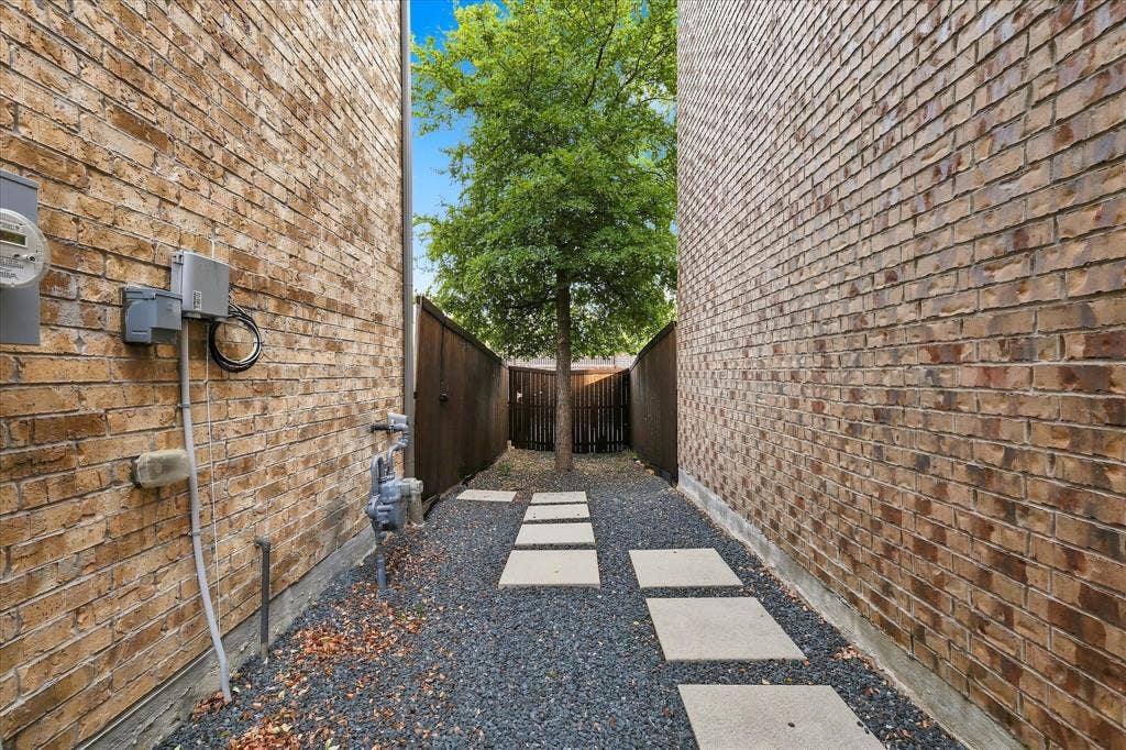 614 Ansley Way, Allen, TX 75013 Side yard featuring tan brick exterior walls, stone paver pathway, gravel ground cover, and enclosed wood fencing