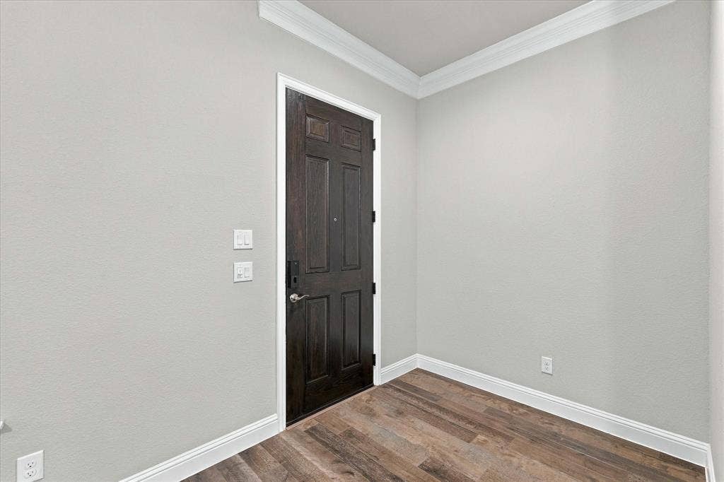 614 Ansley Way, Allen, TX 75013 Dark-toned six-panel door with metallic hardware, neutral wall paint, crown molding, and wood-finish flooring