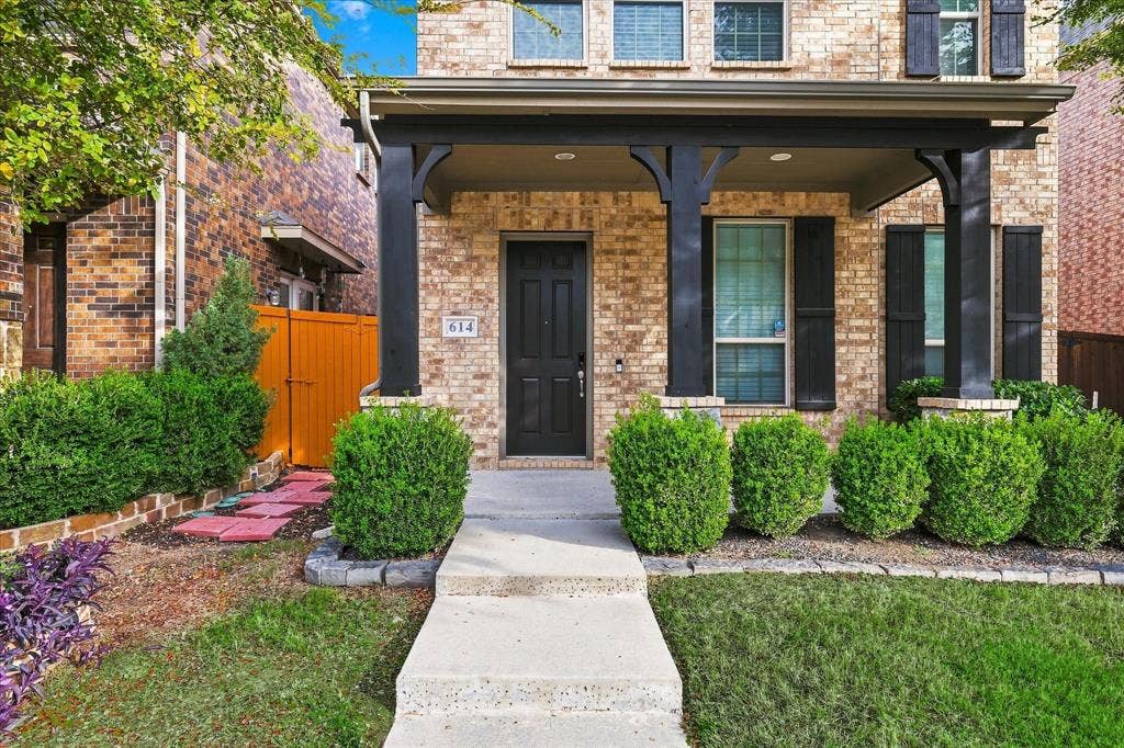 614 Ansley Way, Allen, TX 75013 Brick exterior featuring a covered front porch, dark-toned support columns, shutters, and a manicured landscape