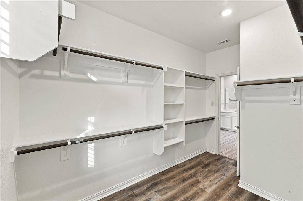 614 Ansley Way, Allen, TX 75013 Walk-in storage area featuring custom white built-in shelving, dark metal hanging rods, and wood-finish flooring with integrated recessed lighting