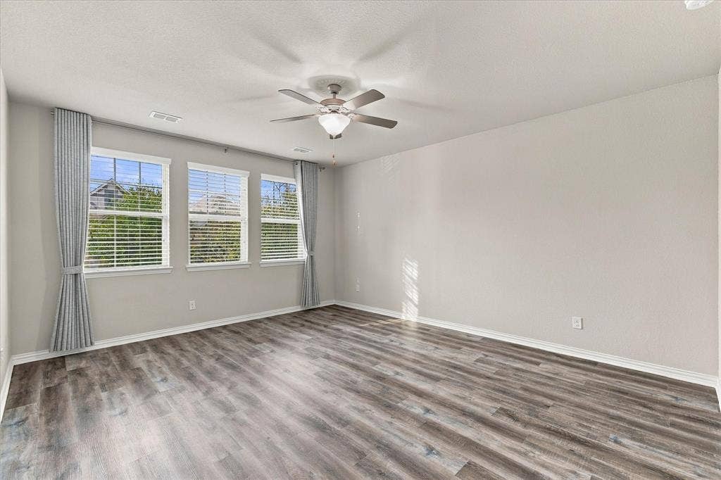614 Ansley Way, Allen, TX 75013 Room featuring wood-finish flooring, three windows with horizontal blinds, and a multi-blade ceiling fan