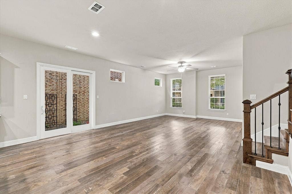 614 Ansley Way, Allen, TX 75013 Open-concept interior featuring wood-finish flooring, sliding glass doors, recessed lighting, double-hung windows, and a staircase with iron balusters and a wood handrail