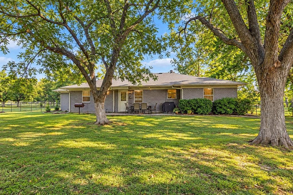 2415 Fannin Street, Greenville, TX 75401 Rear exterior view of the home featuring the backyard and patio area.