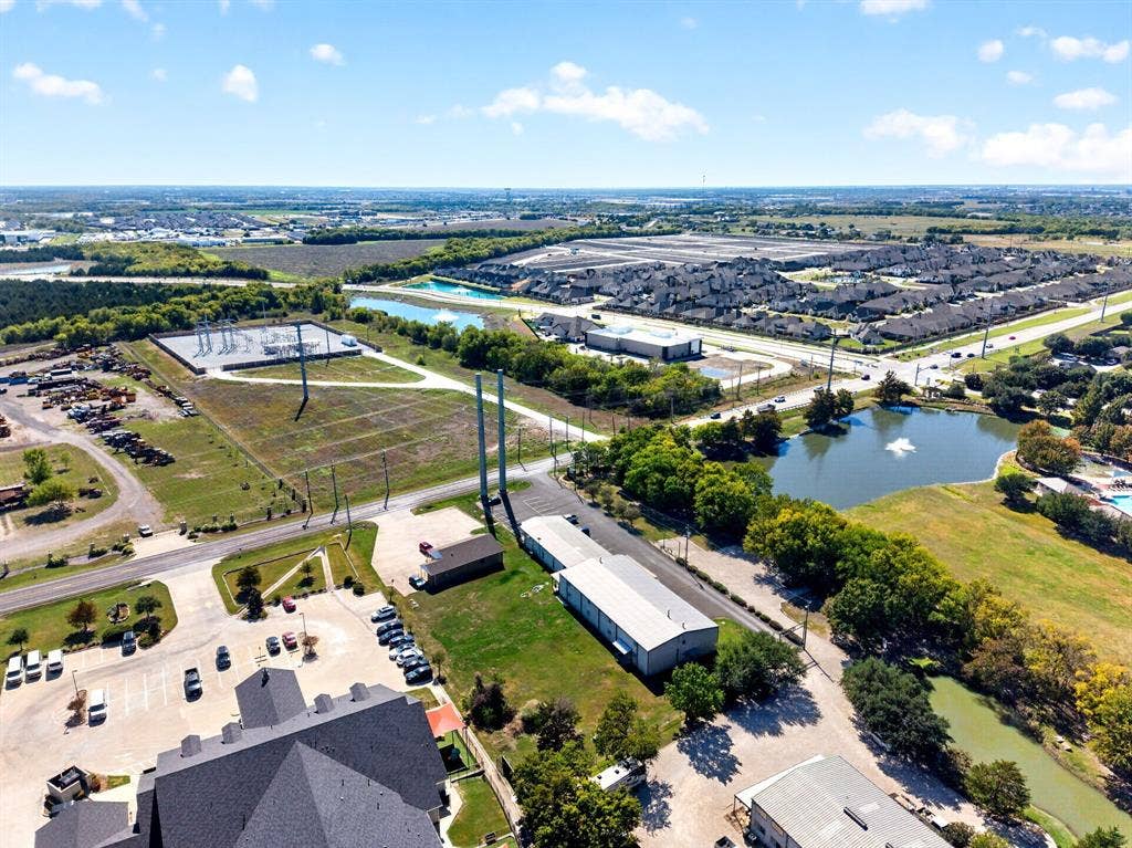 911 W Holiday Drive, Fate, TX 75132 Aerial perspective featuring multiple industrial-style structures, paved parking areas, and surrounding bodies of water
