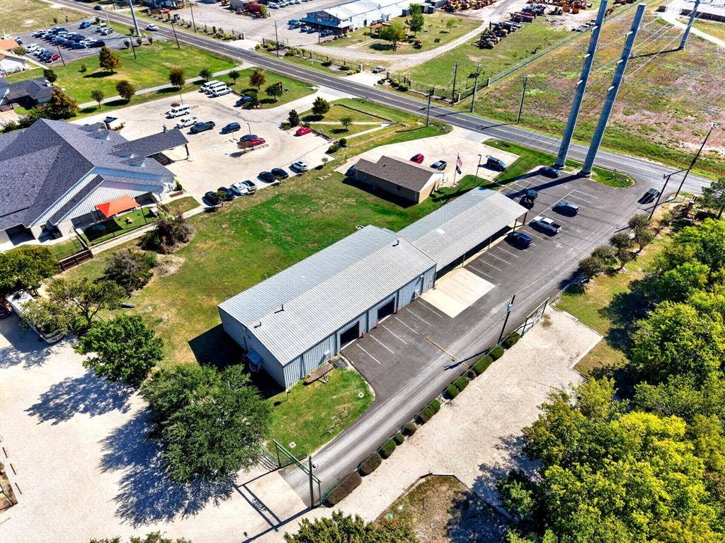 911 W Holiday Drive, Fate, TX 75132 Industrial property featuring a metal building, dedicated covered parking, paved driveway, gated entry, and expansive grounds