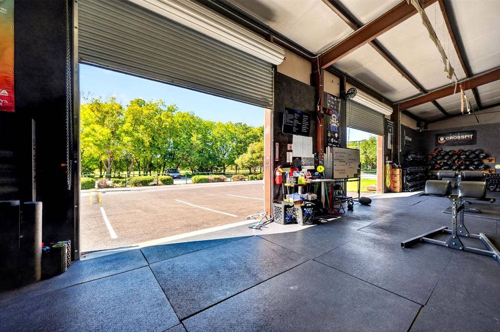 911 W Holiday Drive, Fate, TX 75132 Industrial flex space featuring high ceilings with exposed steel beams, durable rubber flooring, and large roll-up bay doors