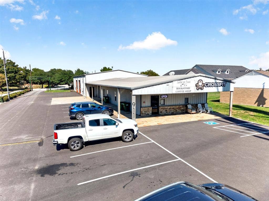 911 W Holiday Drive, Fate, TX 75132 Commercial property exterior featuring metal siding, stone veneer accents, a covered entrance, and a dedicated asphalt parking area