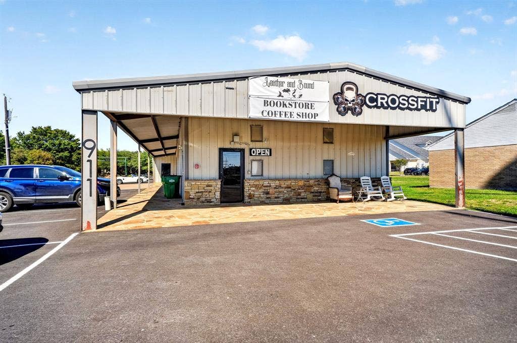 911 W Holiday Drive, Fate, TX 75132 Commercial exterior featuring metal siding, stone veneer base, covered porch with stone paving, and asphalt-paved parking lot