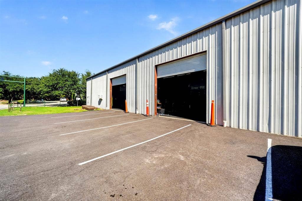 911 W Holiday Drive, Fate, TX 75132 Industrial exterior featuring metal siding, dual roll-up bay doors, and paved surface parking