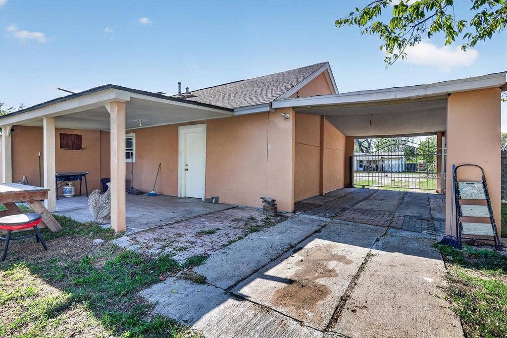 Exterior featuring a covered patio, a concrete driveway, a dedicated carport, and a gated perimeter