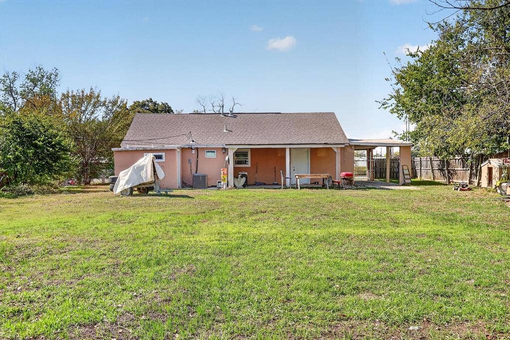 Rear exterior featuring a covered patio, attached carport, and an expansive grass lawn