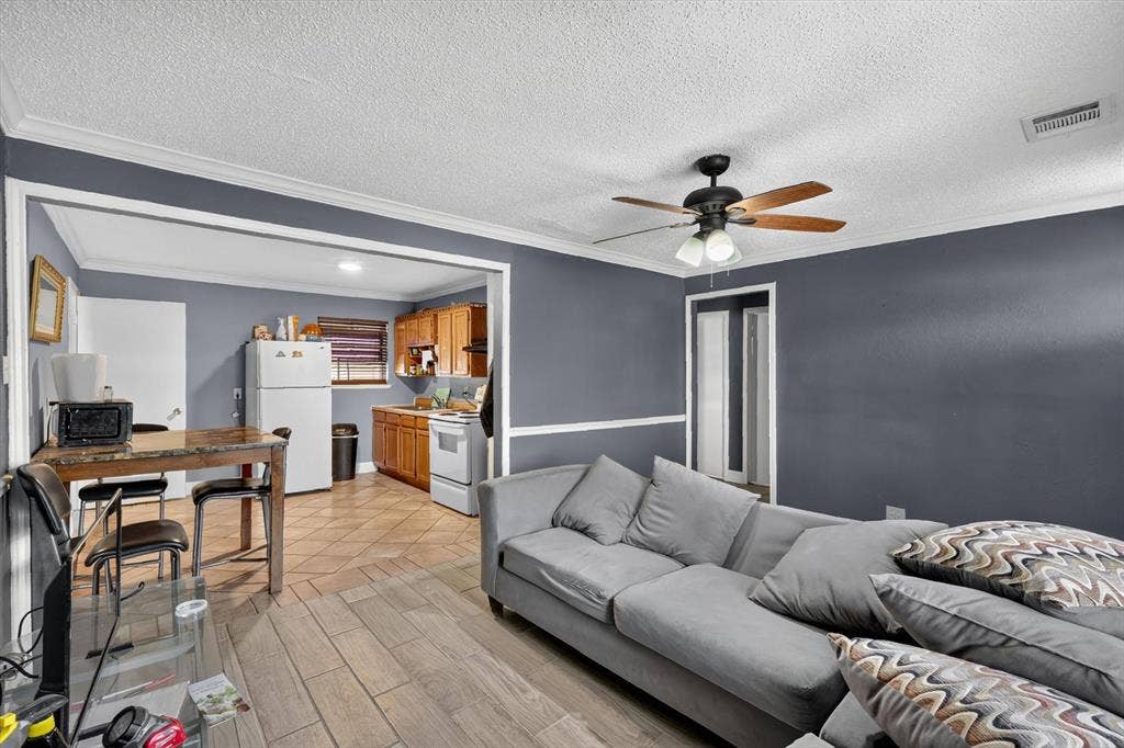 Interior space featuring wood-finish flooring, crown molding, chair rail trim, and a multi-light ceiling fan