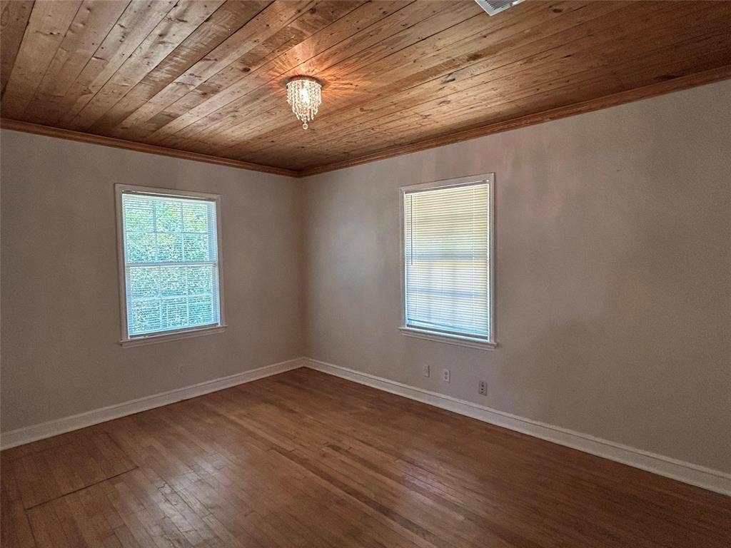 Room featuring wood-plank ceiling, wood-finish flooring, and a crystal-style flush-mount light fixture