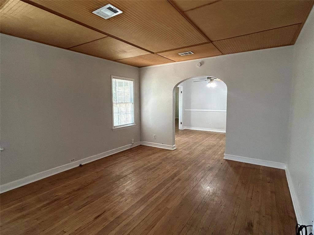 Interior space featuring wood-finish flooring, a paneled wood ceiling, and an arched entry