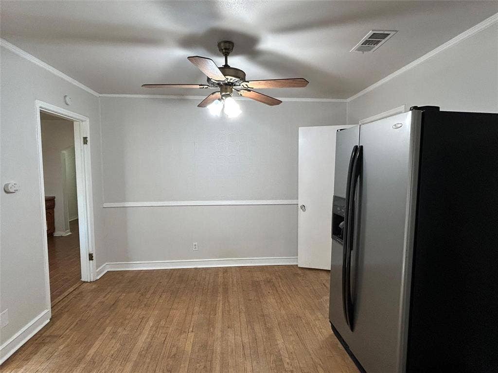 Wood-finish flooring, chair rail molding, and a multi-blade ceiling fan with integrated lighting