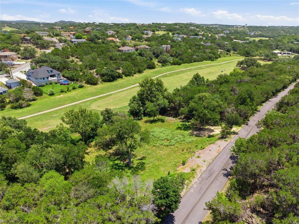 Expansive parcel of land featuring mature trees, native vegetation, and bordering a grassy fairway