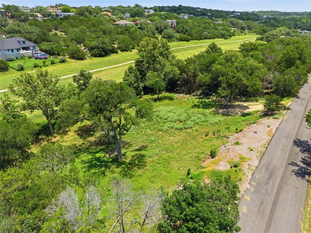 Vacant lot featuring paved road frontage, established native trees, and expansive green space