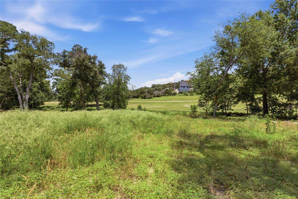 Expansive open lot featuring native vegetation, mature oak trees, and rolling grassy terrain