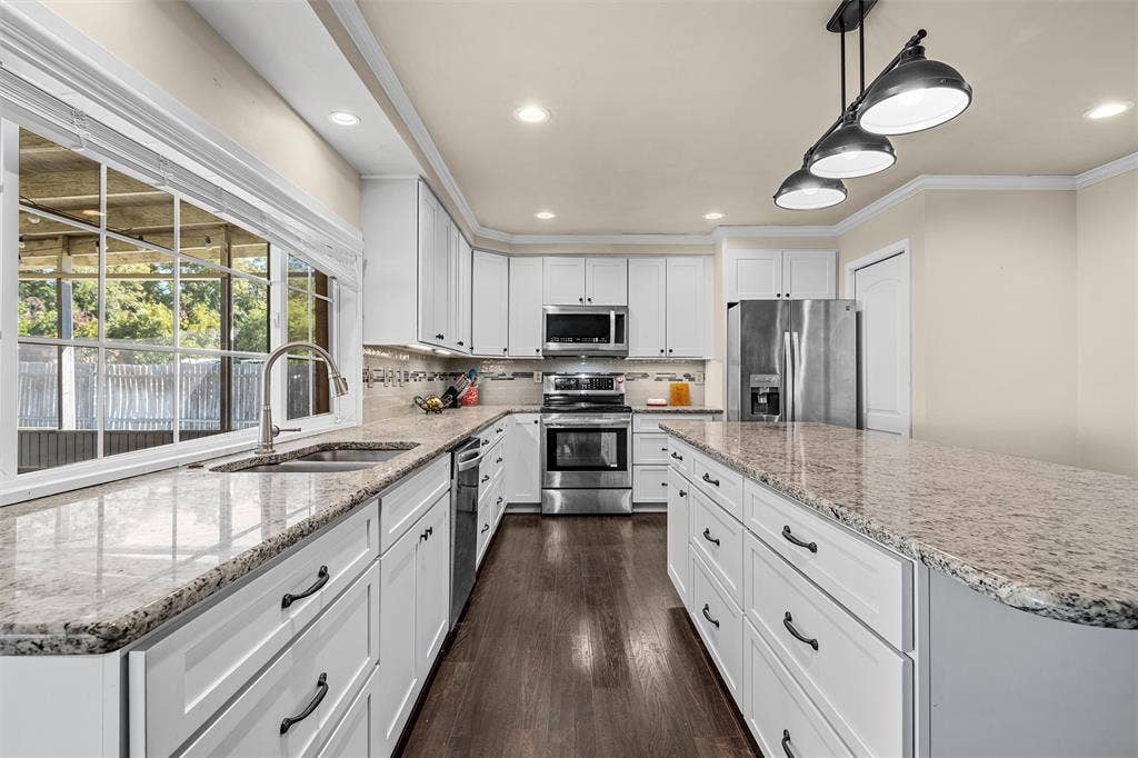 Kitchen featuring white cabinetry, stone countertops, stainless steel appliances, wood-finish flooring, and multi-light pendant lighting