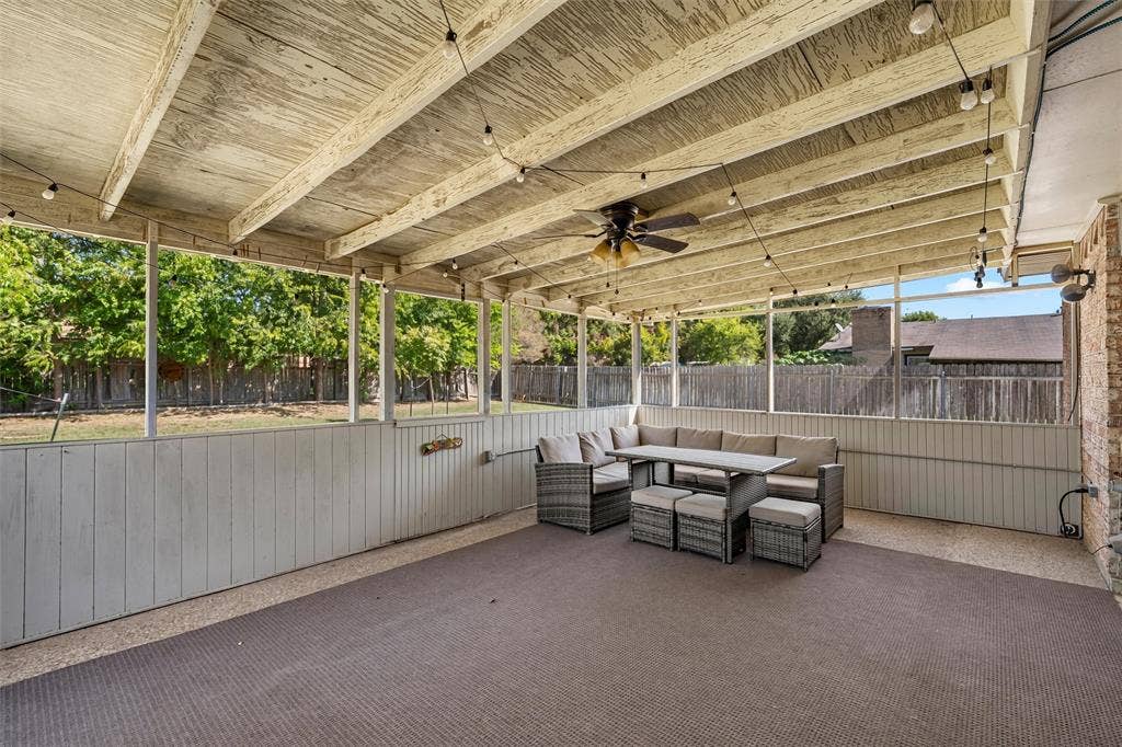 Screened-in patio featuring an exposed rafter ceiling, ceiling fan, and concrete flooring