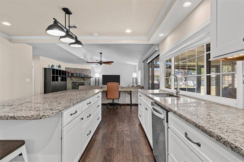 Kitchen featuring white cabinetry, stone-surface countertops, wood-finish flooring, a stainless steel faucet, and pendant lighting