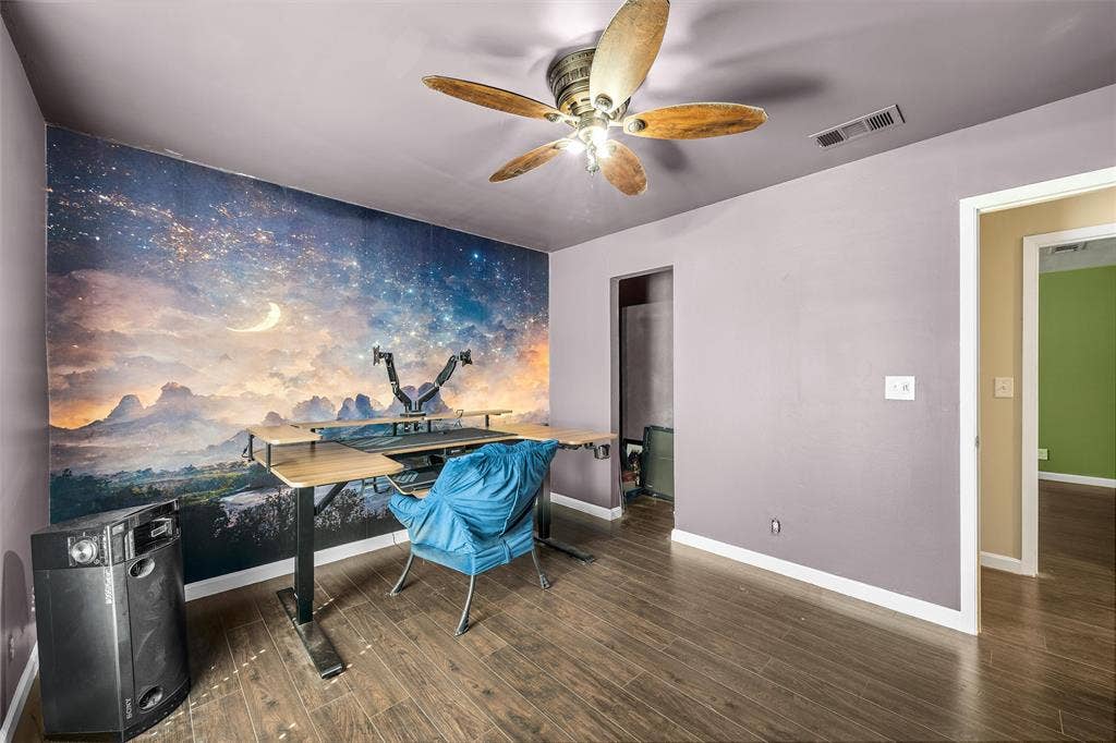Wood-finish flooring, accent wall with a celestial-themed mural, and a five-blade ceiling fan with integrated lighting