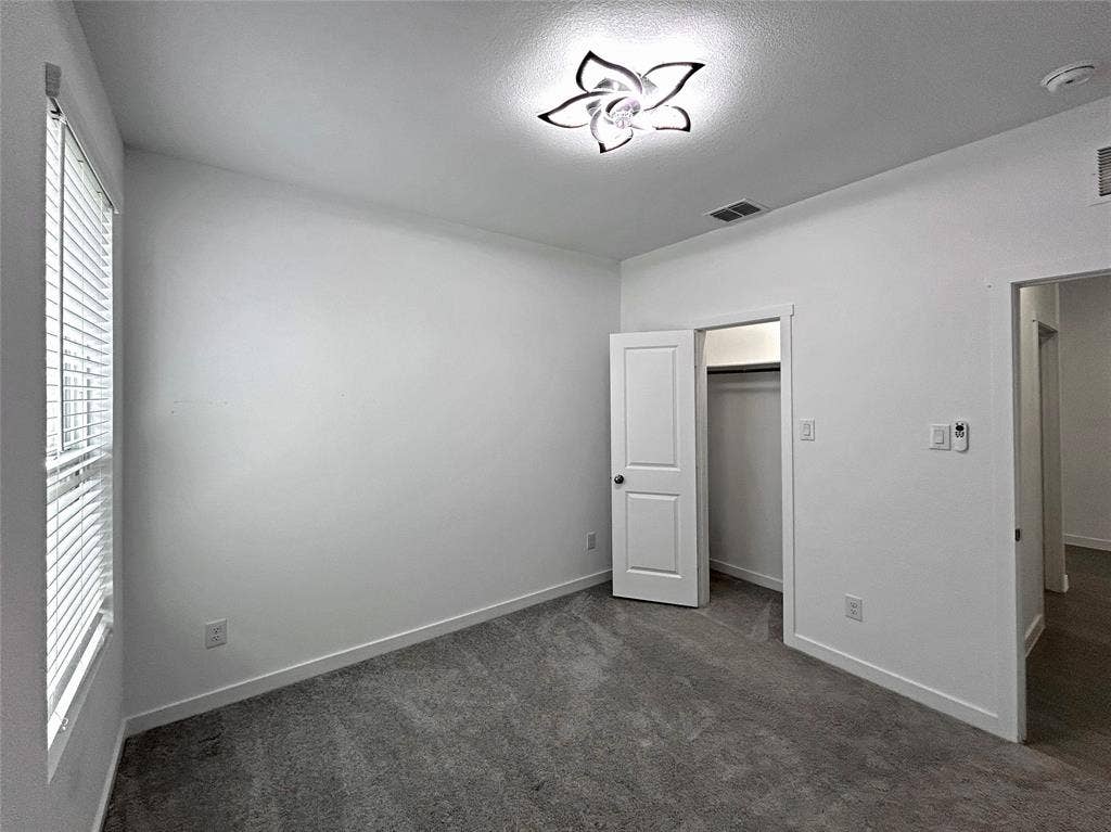 2504 Clyde Road, Celina, TX 75009 Interior space featuring neutral-toned carpeting, a floral-inspired flush-mount ceiling light fixture, horizontal window blinds, and a built-in closet