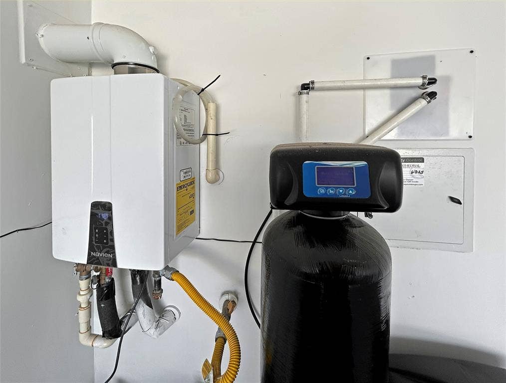 2504 Clyde Road, Celina, TX 75009 Wall-mounted tankless water heater paired with a whole-house water filtration system featuring a digital control interface