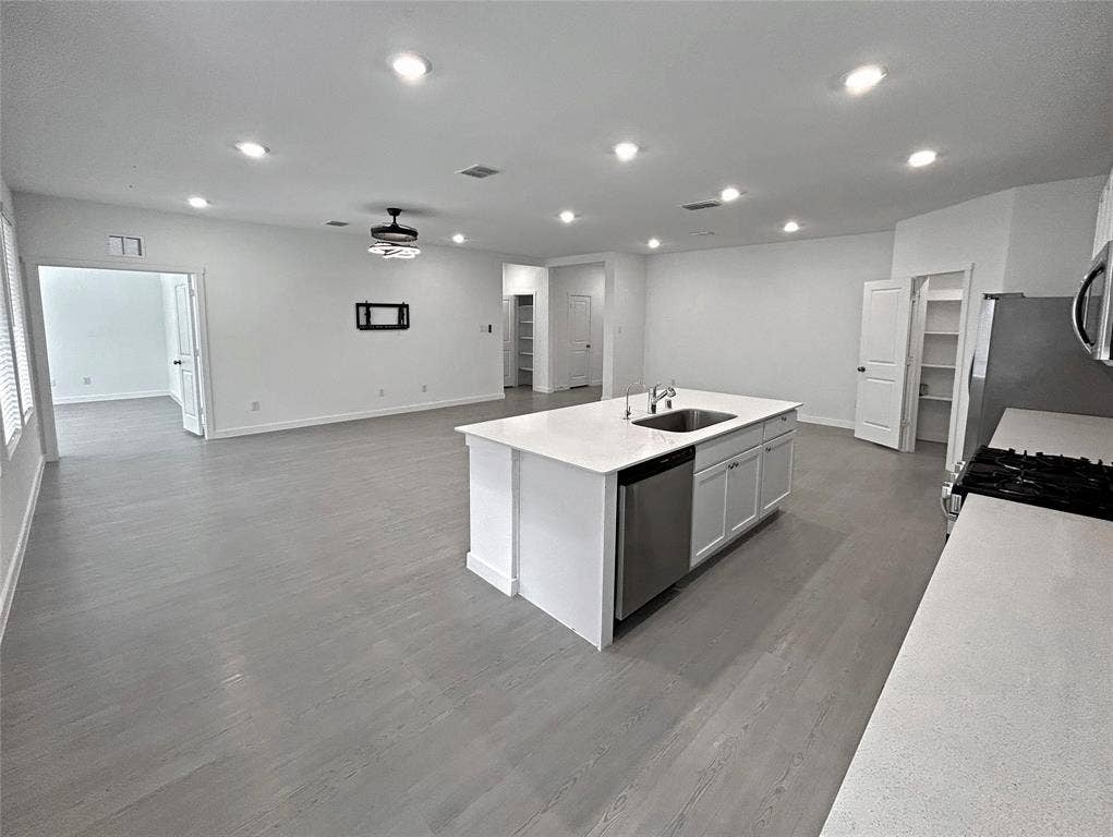 2504 Clyde Road, Celina, TX 75009 Kitchen features an island with a stone-finish countertop, stainless steel dishwasher, undermount sink, recessed lighting, gas range, and luxury vinyl plank flooring