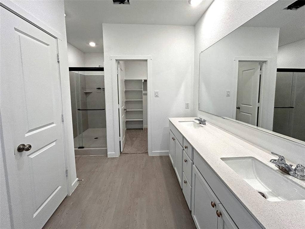 2504 Clyde Road, Celina, TX 75009 Dual vanity with stone-composite countertop, full-width wall mirror, walk-in shower with glass enclosure, and built-in closet shelving