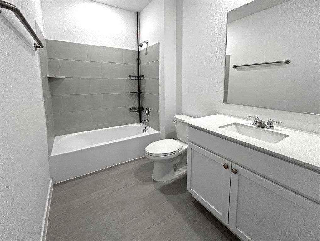 2504 Clyde Road, Celina, TX 75009 A full bathroom features a white vanity with a light-toned countertop, integrated rectangular sink, large wall-mounted mirror, luxury vinyl plank flooring, and a bathtub with gray tile surround