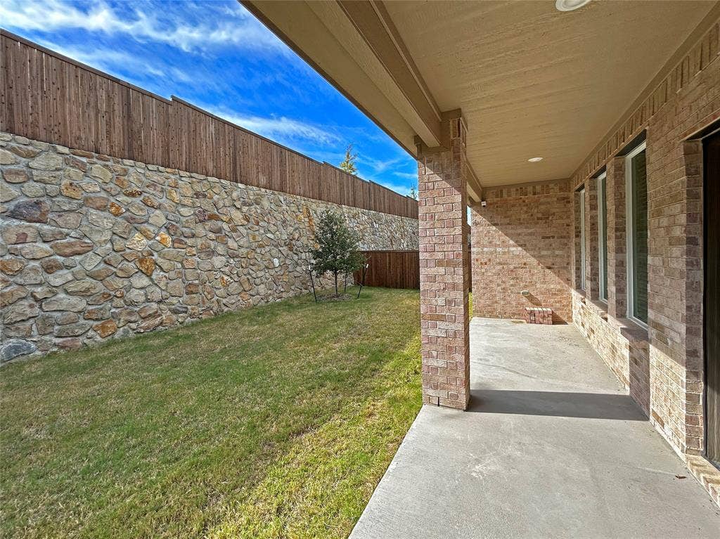 2504 Clyde Road, Celina, TX 75009 Covered concrete patio featuring recessed lighting, brick exterior walls, and an exterior stone masonry privacy wall