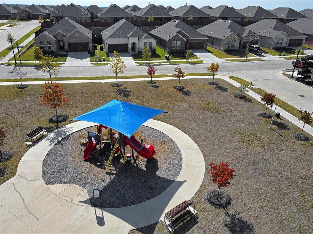 2504 Clyde Road, Celina, TX 75009 The house overlooks a community park, which features a playground structure with a blue shade canopy, circular concrete walkway, and dedicated outdoor benches