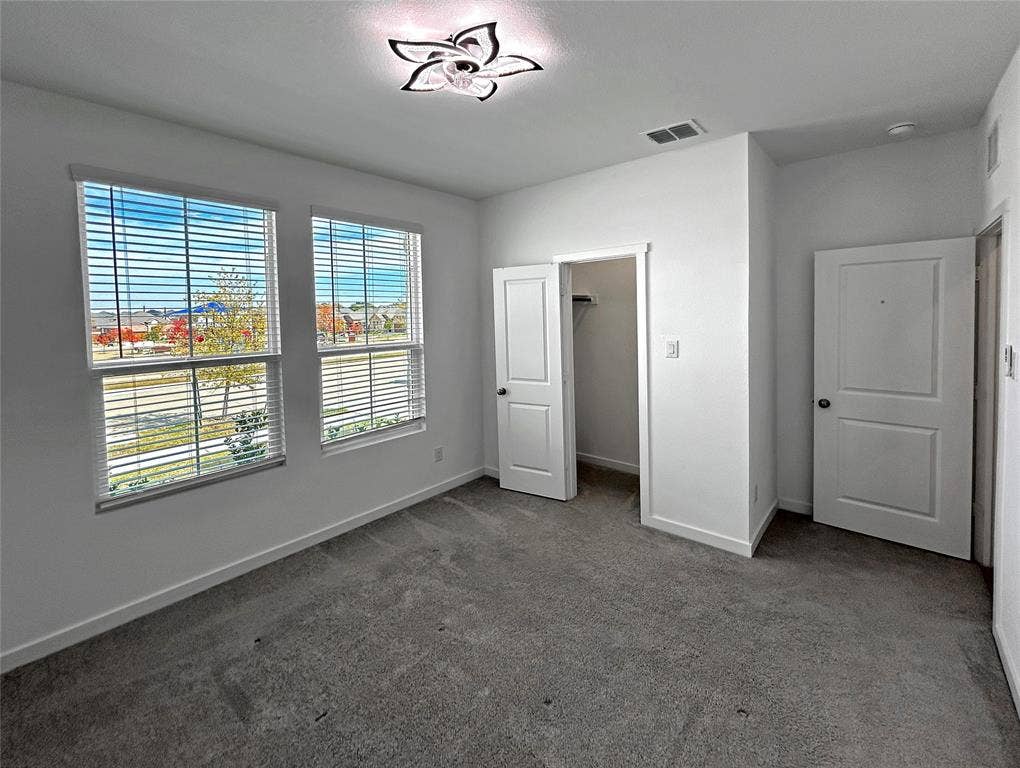 2504 Clyde Road, Celina, TX 75009 Front bedroom features two windows with horizontal blinds that overlook the neighborhood park, a walk-in closet, and a decorative ceiling light fixture